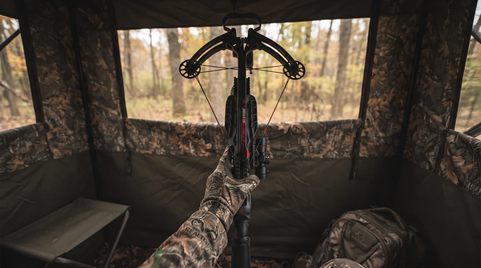 Short compact crossbow held upright inside a ground blind for scale