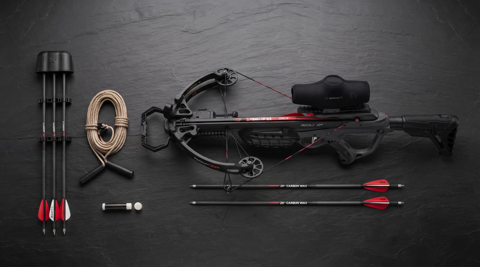 Flat lay of a crossbow package with quiver, two arrows, rope cocking device and wax