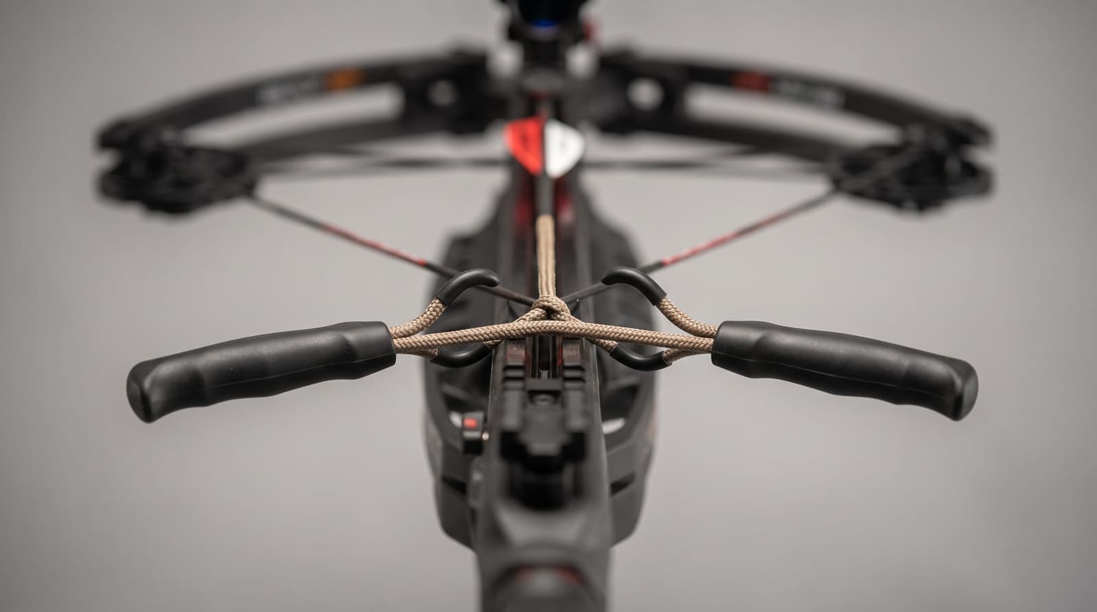 Close-up of a rope cocking device laid across the rail of a compact crossbow