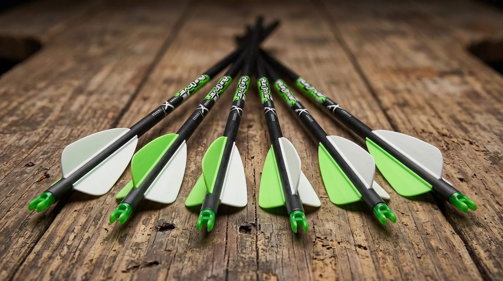 Six Carbon Express PileDriver crossbow bolts fanned out on a wooden bench, showing the nock ends and large vanes
