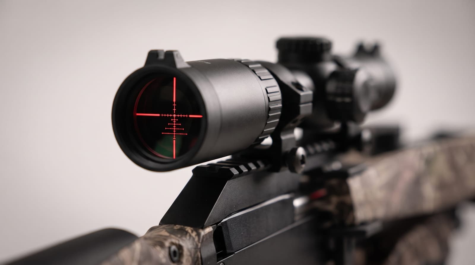High-end commercial macro product photograph, close-up of a crossbow's illuminated scope with a glowing red reticle clearly
