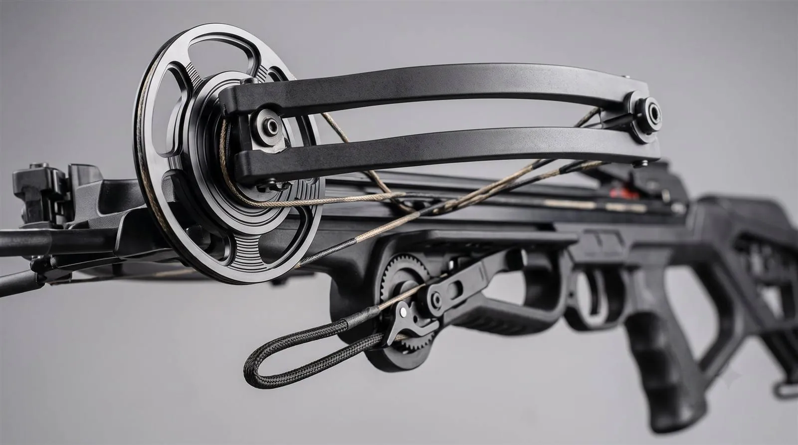 Close-up of a compound crossbow cam and integrated cocking mechanism on a studio background