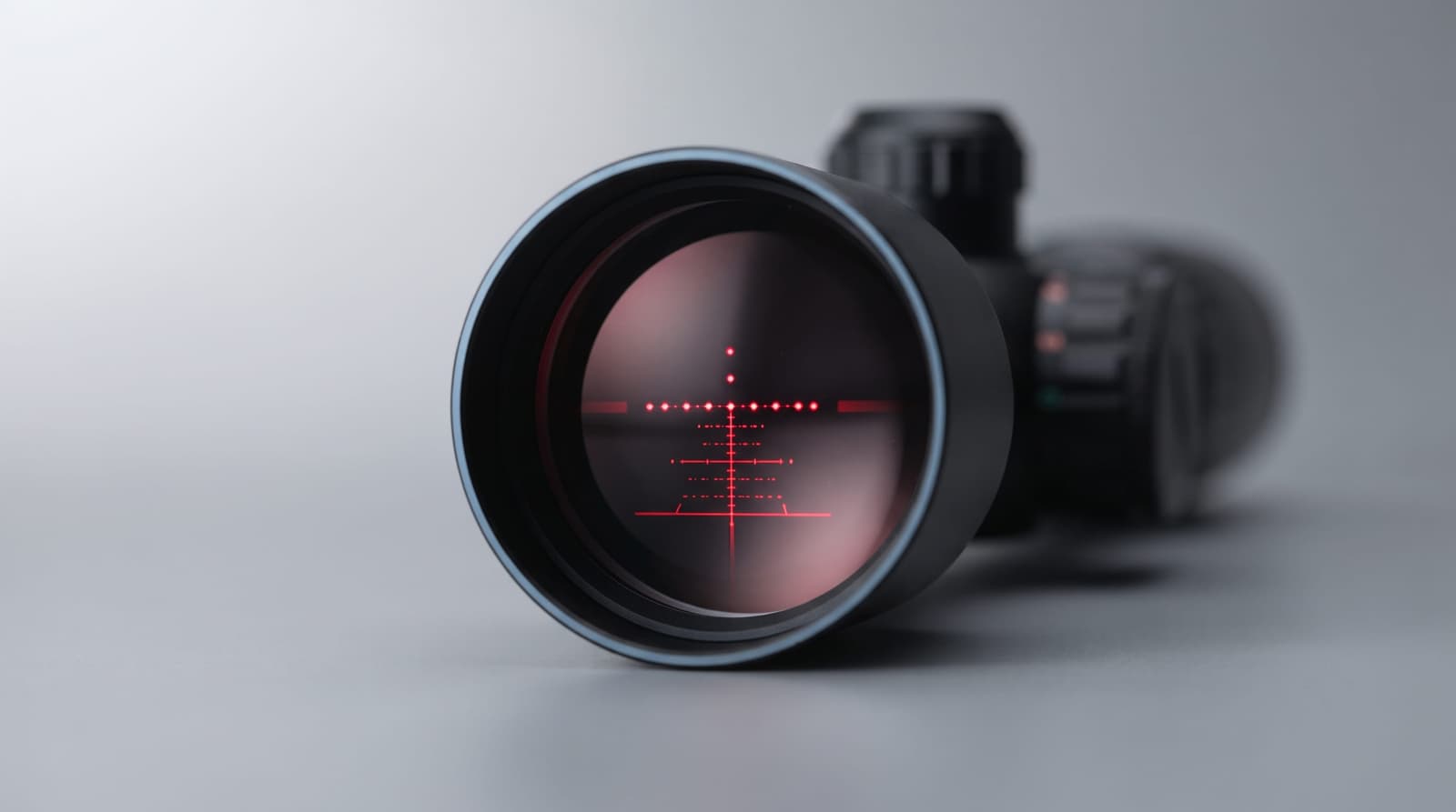 High-end commercial macro product photograph, close-up looking into the objective end of a crossbow scope, a small glowing
