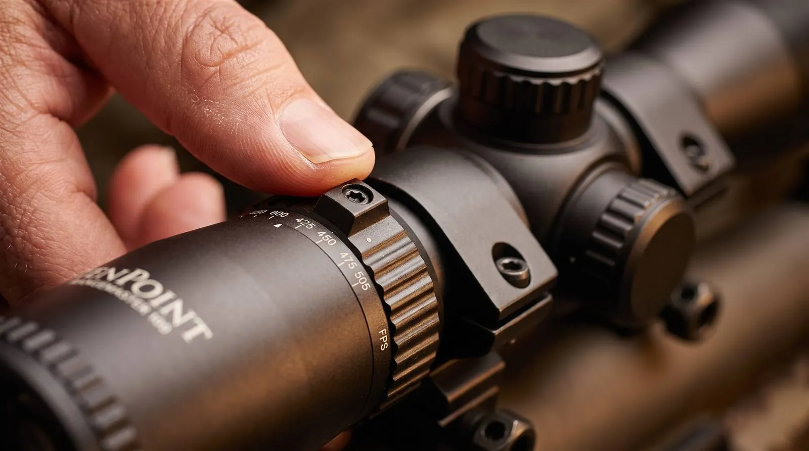Hand turning the illumination rheostat dial on the RangeMaster 100 scope