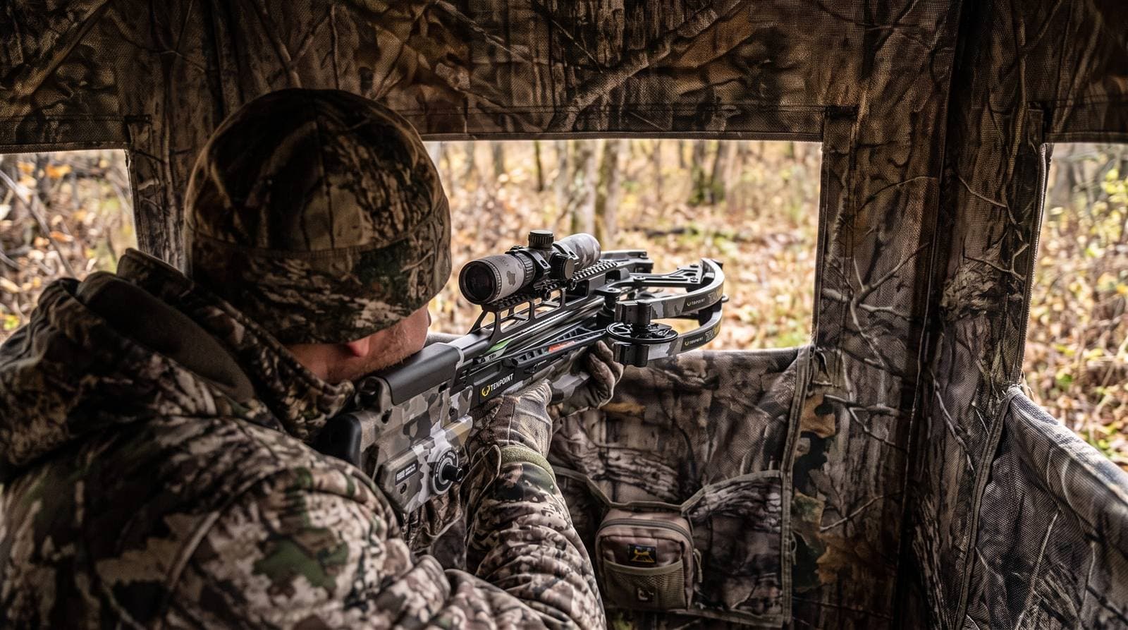 Compact TenPoint TX Ultra 26.5 crossbow being handled in the confined space of a ground blind
